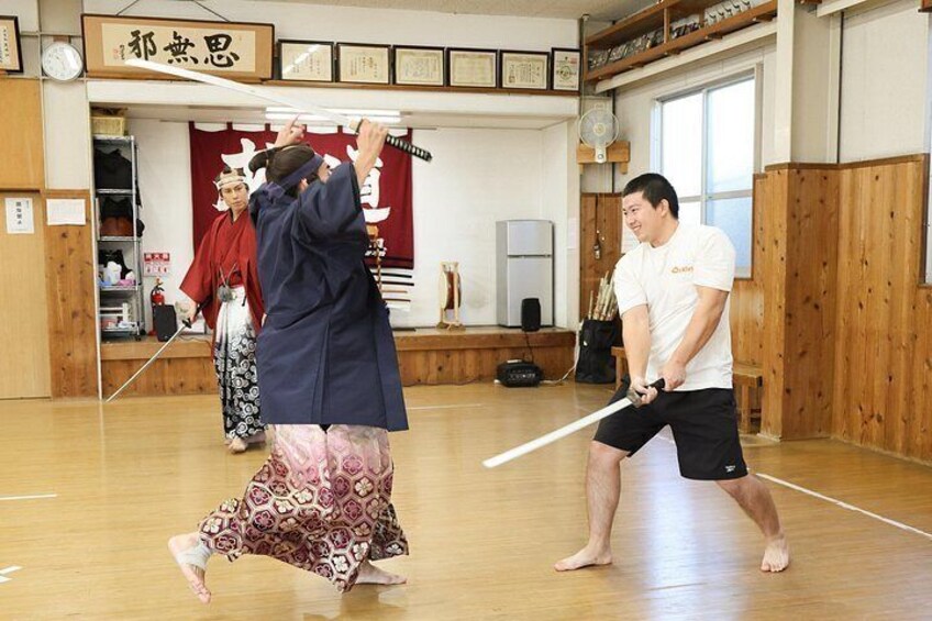 En träningssession i kampsport där deltagarna övar med svärd i en dojo. 5