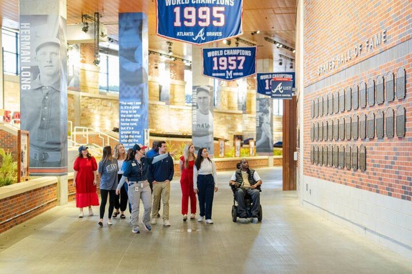 Een museuminterieur met een bakstenen muur waarop plaquettes, een groot beeld en banners hangen. 1