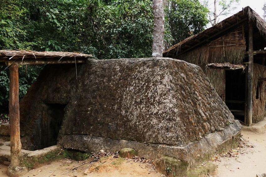 A traditional stone house with a thatched roof, surrounded by dense forest. 2