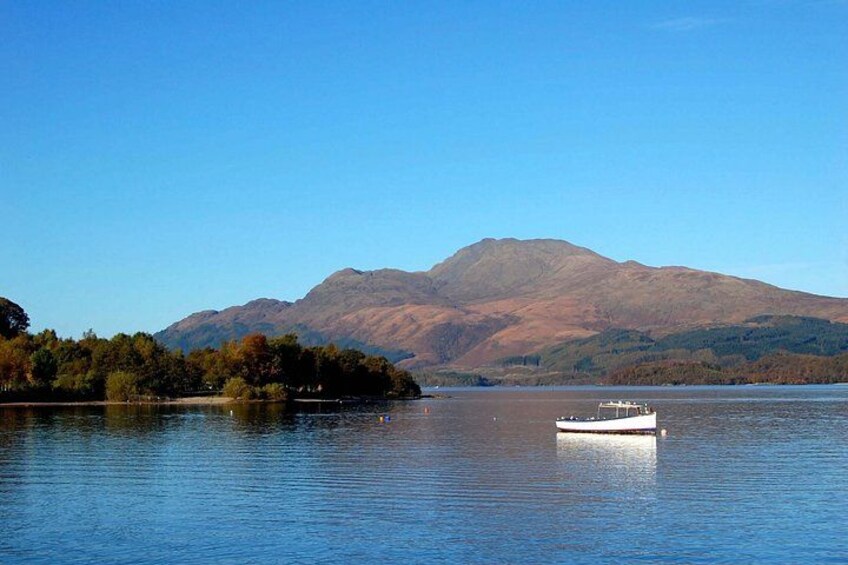 A calm lake with a boat, surrounded by trees and mountains. 2
