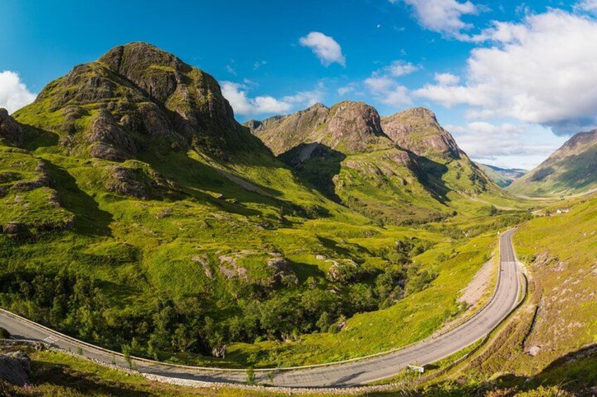 A winding road through a mountainous landscape with lush green hills and rocky outcrops. 3