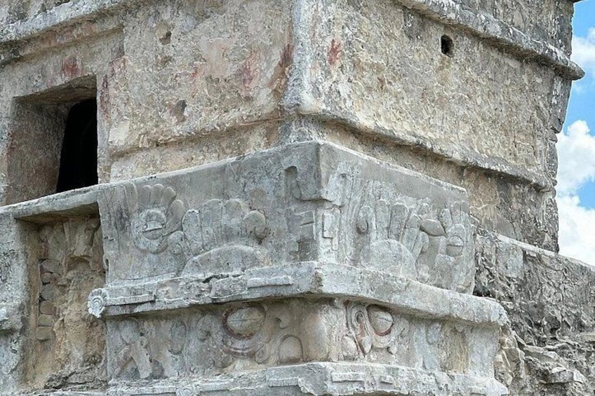 A stone structure with carvings, a partially open doorway, and a clear sky. 3