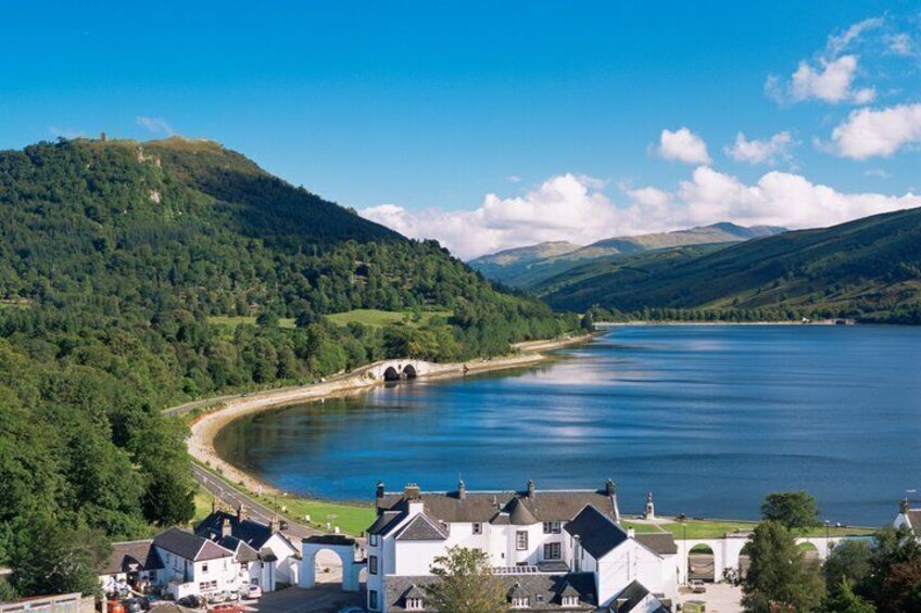 A lake surrounded by hills, a bridge, and a small village with houses. 4