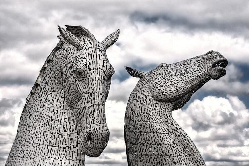 Twee grote paardenbeelden van baksteen voor een bewolkte lucht. 3