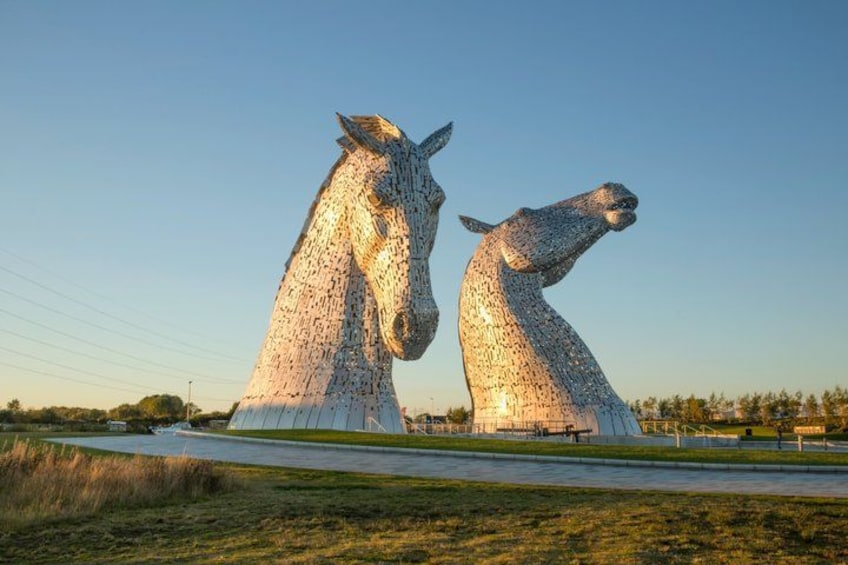 Two large horse sculptures in a grassy field with a clear sky. 2