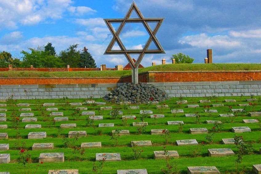 A Star of David monument surrounded by a cemetery with gravestones. 1