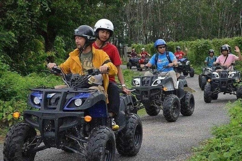 People riding ATVs on a paved path surrounded by greenery. 4