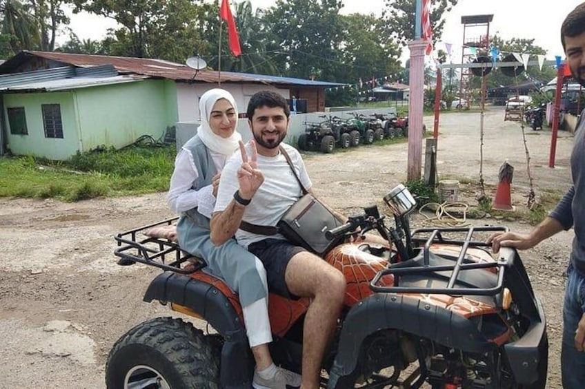 Two people on an ATV with a rural background. 3