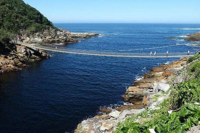 Un paisaje costero con acantilados rocosos, un muelle que se adentra en el mar y un cielo despejado. 4
