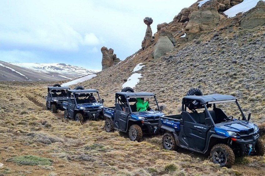 Drei Geländewagen auf felsigem Untergrund mit Schneeflecken und einer markanten Felsformation im Hintergrund. 2