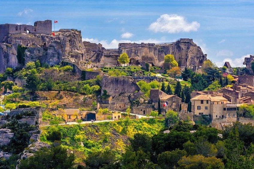 A historic town with a prominent castle on a hill, surrounded by lush greenery and traditional buildings. 1