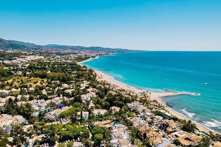 A coastal town with a beach, houses, and a clear blue sea. 3