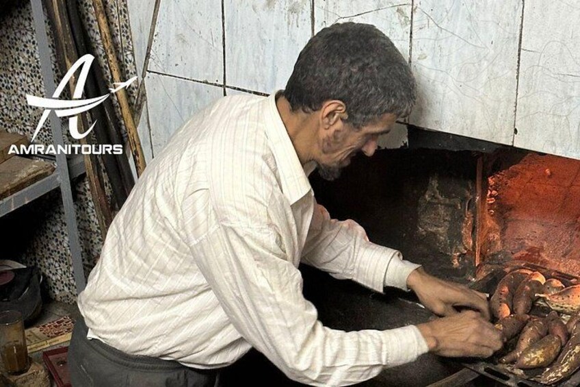 Une personne cuisine dans une cuisine dont le mur est recouvert de carreaux et où l’on aperçoit une étagère à l’arrière-plan. 3