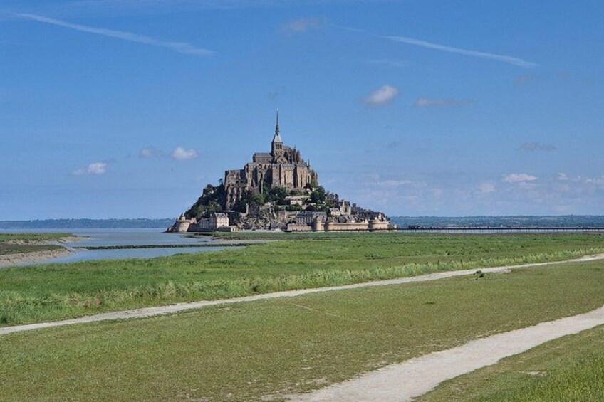 A historic castle on a grassy island with a clear sky. 1