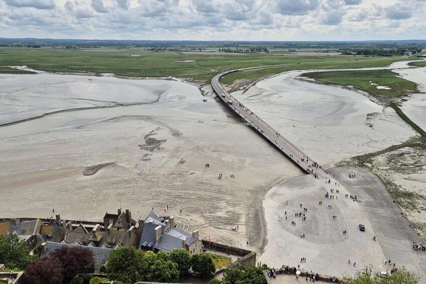 A coastal landscape with a long, straight road curving through it, surrounded by sandy areas and a few buildings. 2
