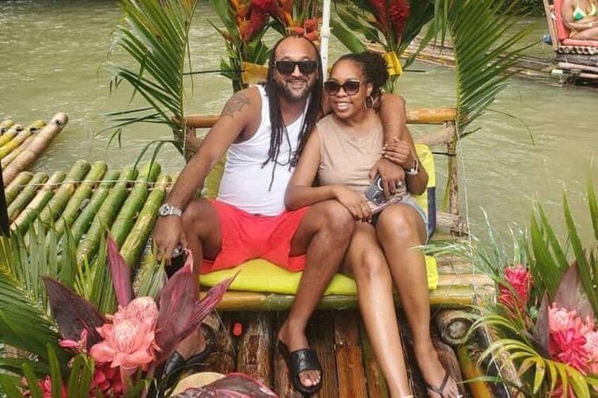 Two people sitting on a boat with a tropical setting, surrounded by greenery and water. 5