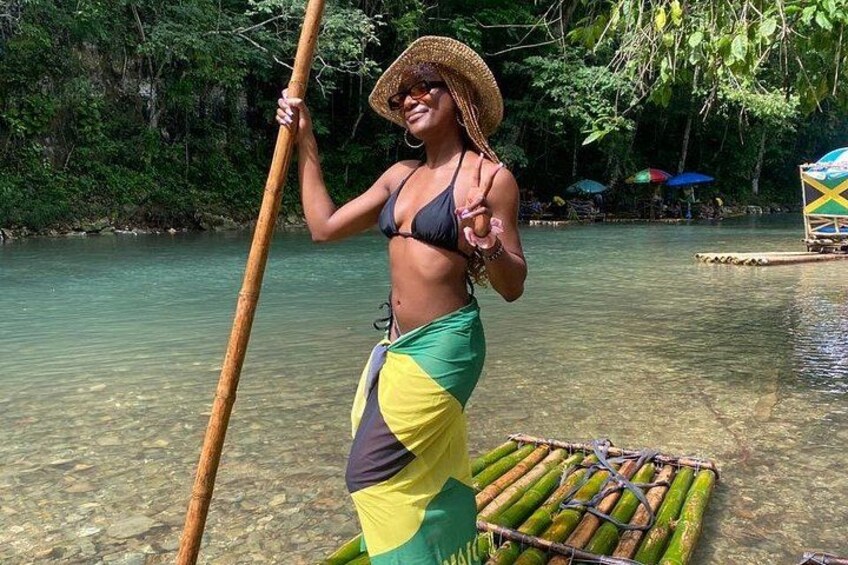 A person standing on a floating platform in a river, holding a long pole. 4
