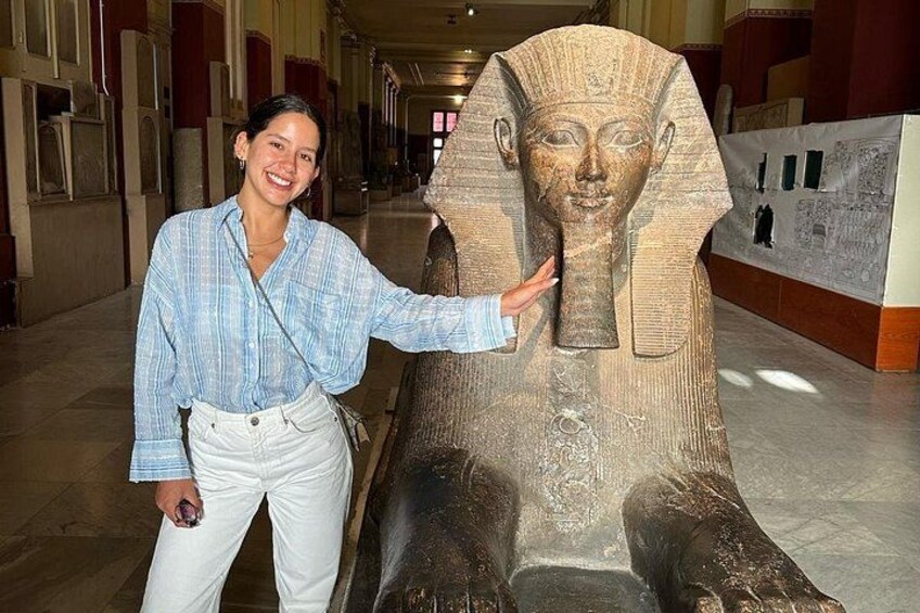 A person standing next to a large ancient Egyptian sarcophagus. 4
