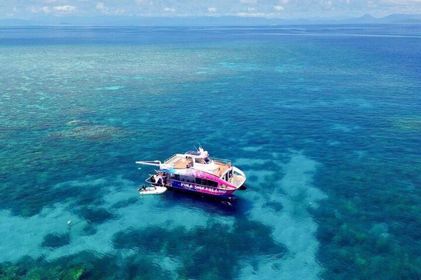 Un bateau sur une eau turquoise et limpide, avec des récifs coralliens visibles. 1