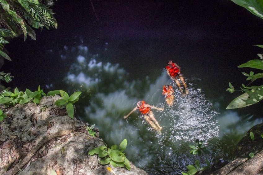 Three people jumping into a river surrounded by foliage. 2