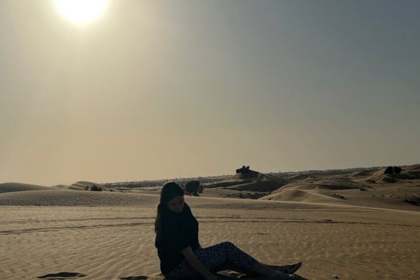 A person sitting on sand dunes with a desert landscape in the background. 5