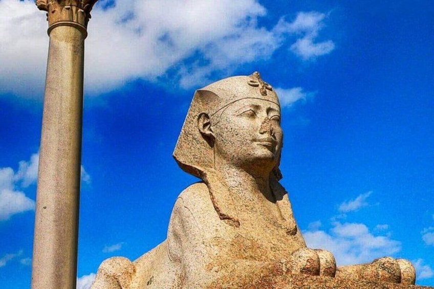 A large stone statue of a seated figure with a headdress, set against a clear blue sky. 5