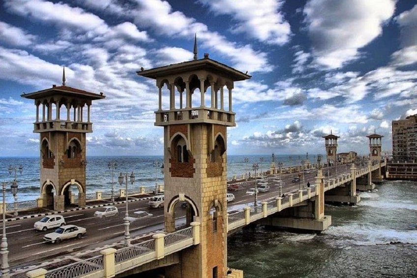 A bridge with towers, a road, and a body of water under a cloudy sky. 4