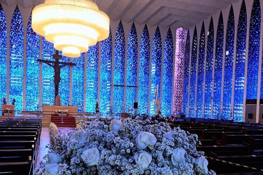 Ein Kircheninneres mit einem großen Kronleuchter, Reihen von Kirchenbänken und einer Blumenkomposition. 4