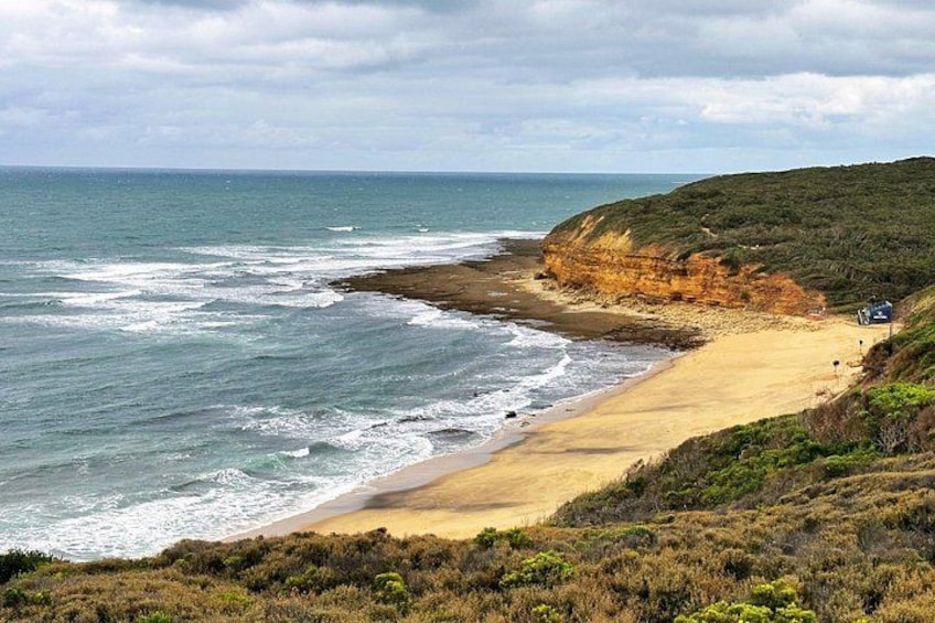 A coastal landscape with a sandy beach, rocky cliffs, and the ocean. 2