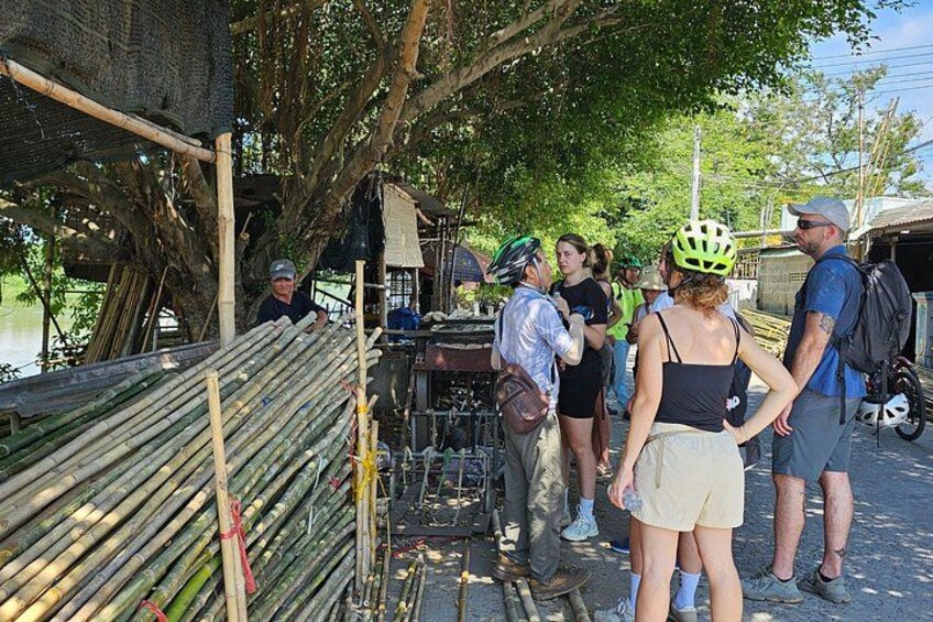 A group of people standing near a bamboo structure, some wearing helmets, and a person in a blue shirt. 3