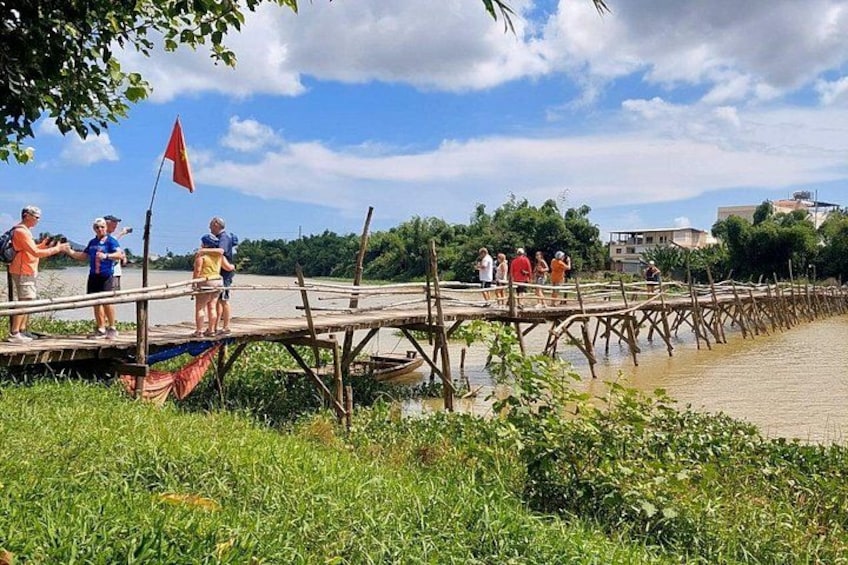 A wooden bridge over water with people standing on it. 1