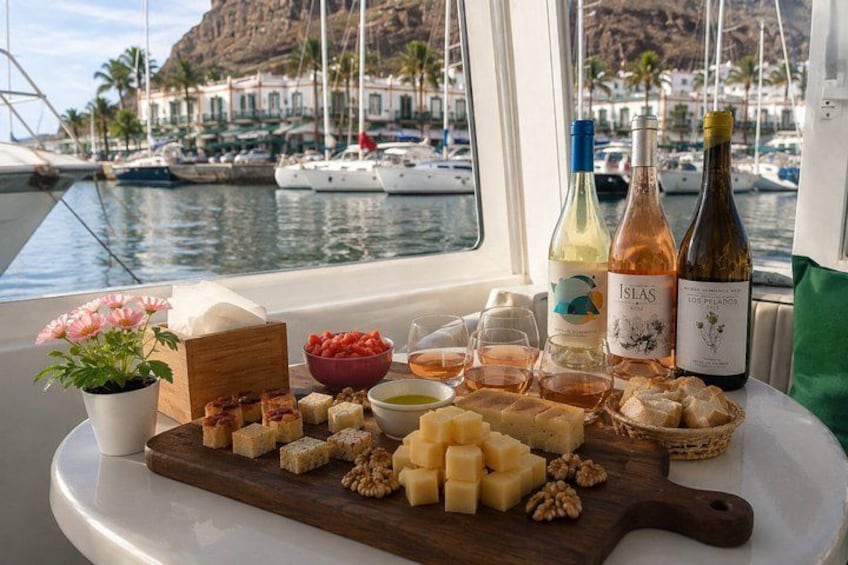 Un bote con una mesa dispuesta con quesos, nueces y botellas de vino. 1