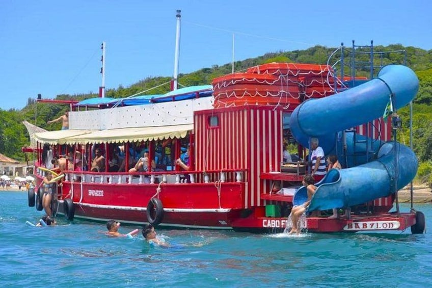 Un bateau rouge et blanc avec un toboggan bleu, et des gens qui nagent dans l’eau. 3