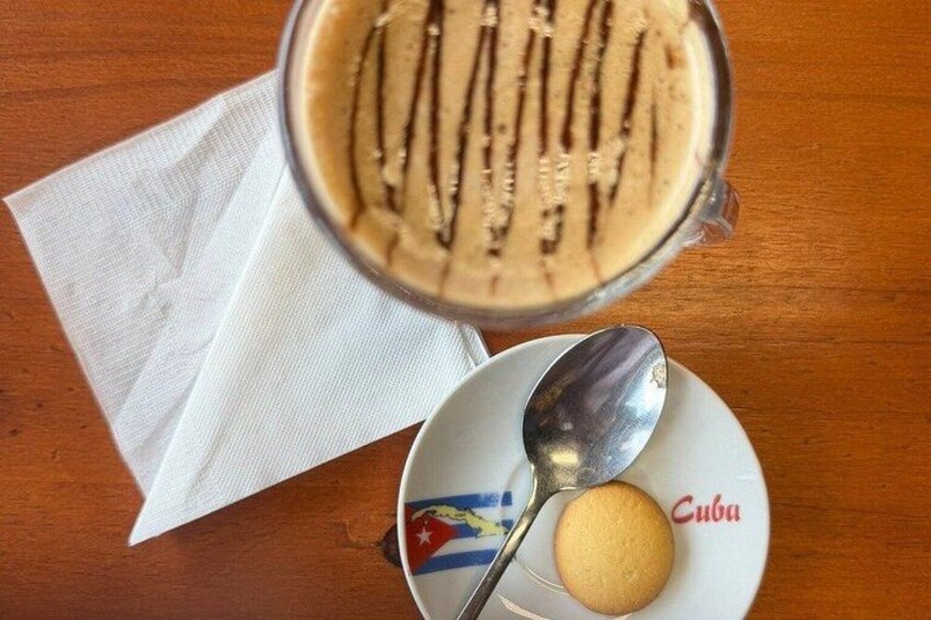 En glasmugg med en skummande dryck, en sked, en kaka och en tallrik med en flagga och ordet ”Cuba”. 5