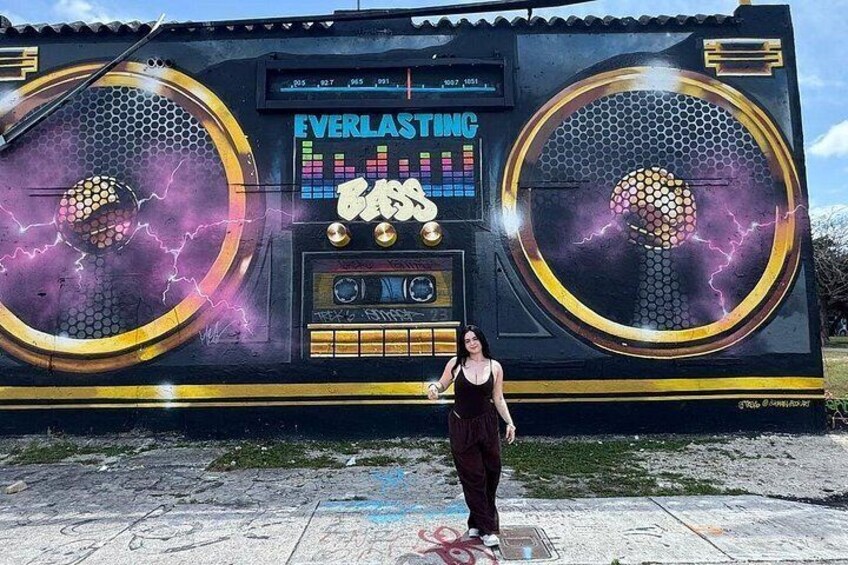 A large outdoor speaker with the words 'EVERLASTING' and 'BASS' on it, and a woman standing in front of it. 1