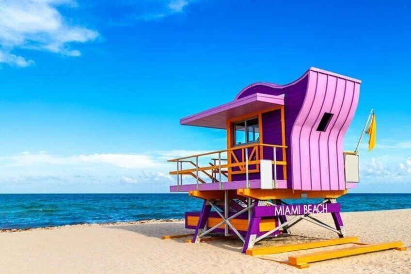 Ein bunter Rettungsschwimmturm am Strand von Miami, im Hintergrund ein klarer, blauer Himmel und das Meer. 1
