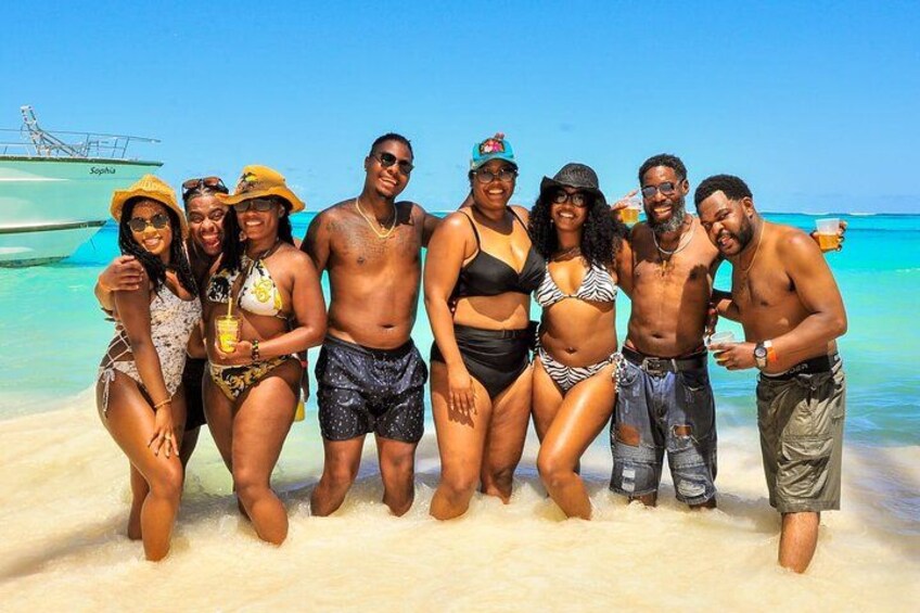 A group of people on a beach with clear blue water and a boat in the background. 5