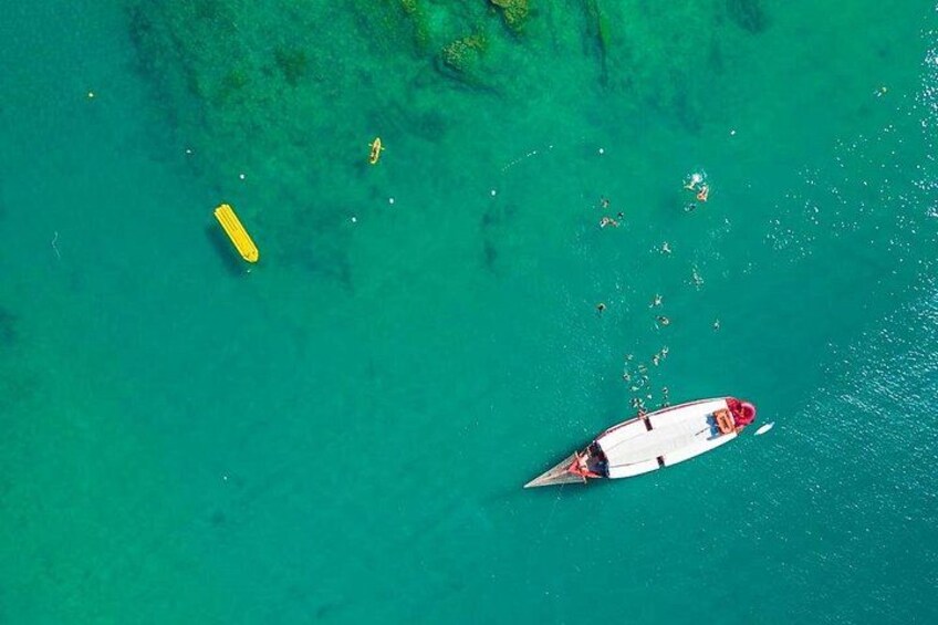Een klein zeilbootje op turquoise water met een gele boei in de buurt. 4