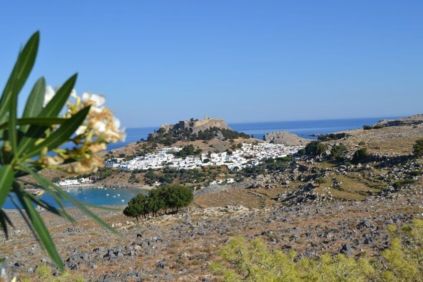 A coastal village with white buildings, a rocky terrain, and a clear blue sky. 1