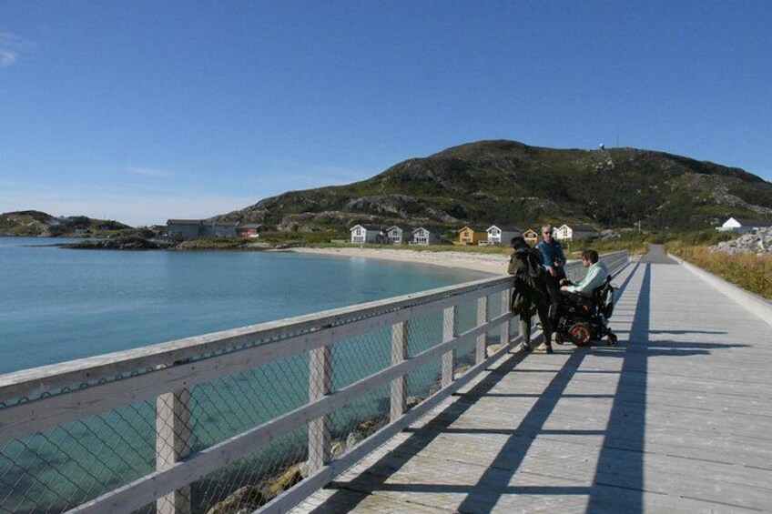 A wooden boardwalk by a body of water with houses in the background. 3