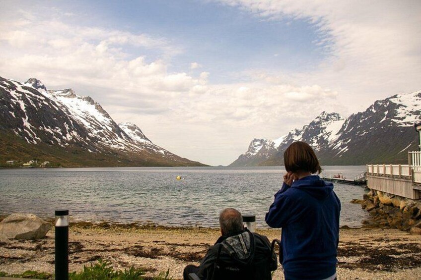 A person taking a photograph of a lake with mountains in the background. 5