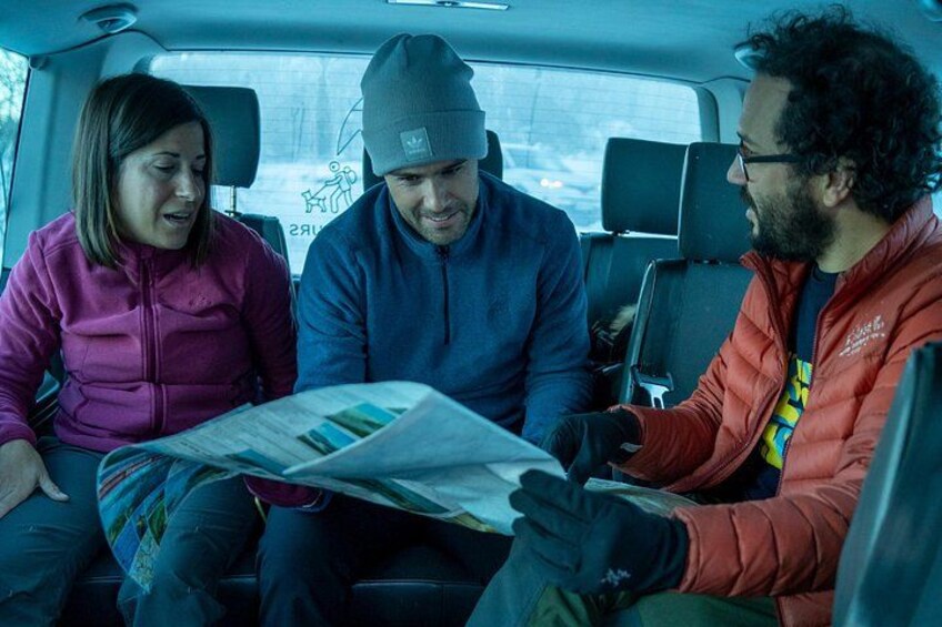 Three people in a vehicle, one holding a map. 2