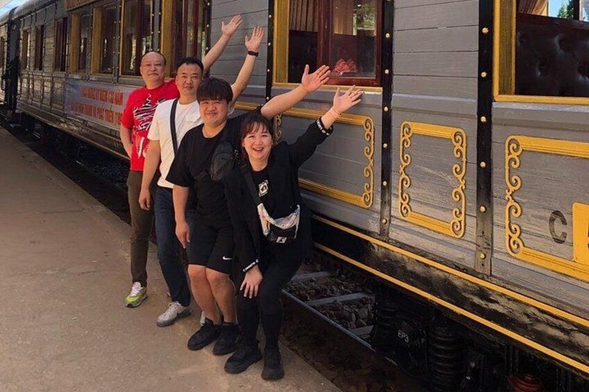 A group of people posing in front of a train with decorative elements and the letter 'C' on the side. 3