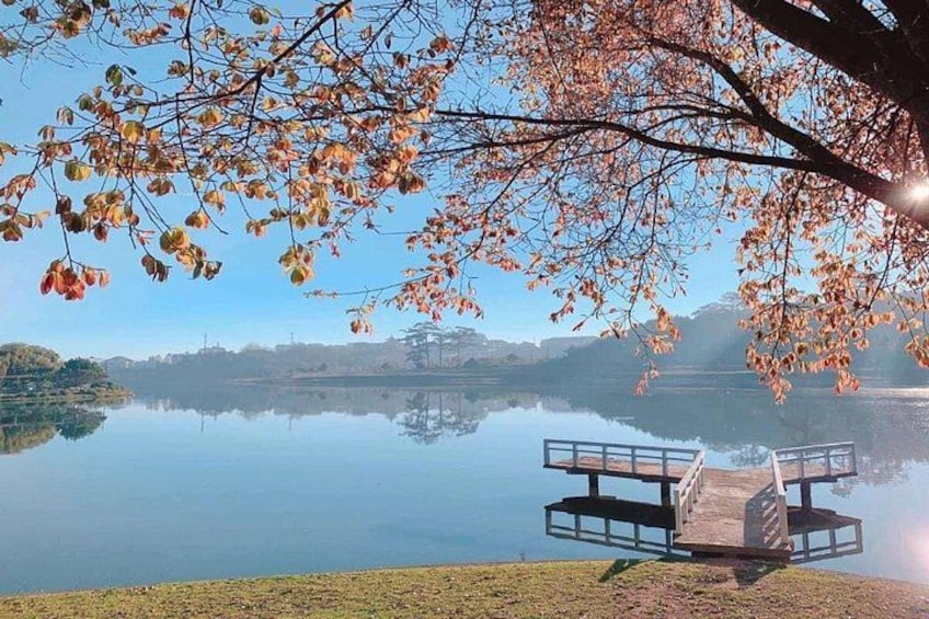 A calm lake with a dock, autumn leaves, and distant hills. 5