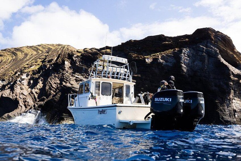 A boat with Suzuki engines on a body of water with rocky cliffs in the background. 2