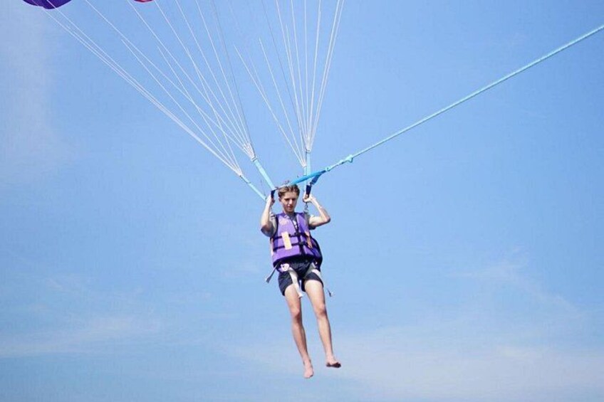 A person paragliding with a parachute harness and a purple vest. 5