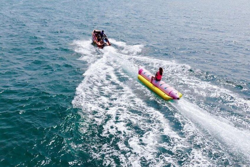 A person on a yellow and pink inflatable raft being towed by a boat. 3