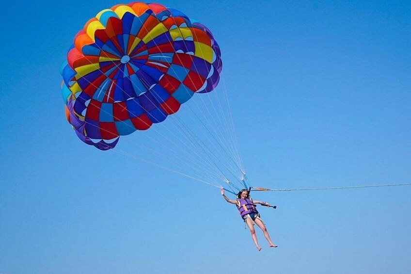A person skydiving with a colorful parachute against a clear blue sky. 4