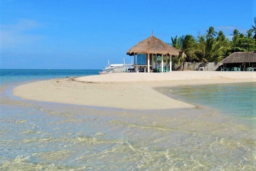 A beach with clear shallow waters, a thatched-roof hut, and a small boat. 5