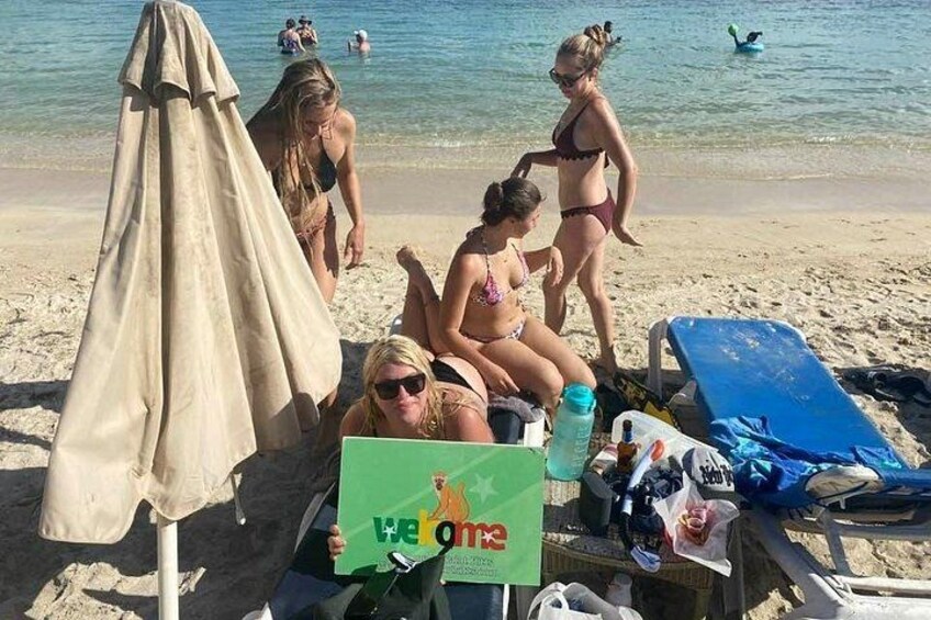 A beach with people sunbathing, a beach umbrella, and a sign with a lion logo. 2
